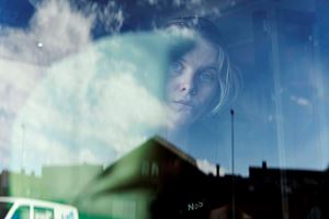 Ung kvinna tittar genom bussfönster med skurduk i handen Foto: Jens Nordström